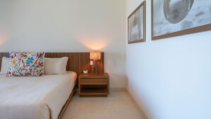 Een hotelkamer met een bed, een nachtkastje met een lamp, en twee ingelijste foto's aan de muur.