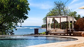 A poolside area with a canopy, lounge chairs, and a view of the ocean. - Penthouse Tau Prima Vista (Punta de Mita)