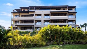 A multi-story building with balconies and a lush garden in front. - Penthouse Tau Prima Vista (Punta de Mita)