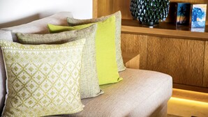 A sofa with patterned cushions, a decorative vase, and framed artwork on a wooden surface. - Penthouse Tau Prima Vista (Punta de Mita)