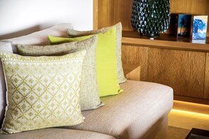 A sofa with patterned cushions, a decorative vase, and framed artwork on a wooden surface. - Penthouse Tau Prima Vista (Punta de Mita)
