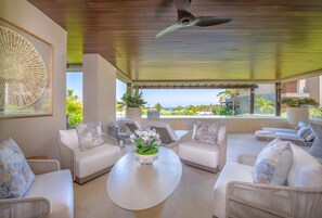 Ein stilvoller Lounge-Bereich mit weißen Möbeln, einem Deckenventilator und Meerblick.