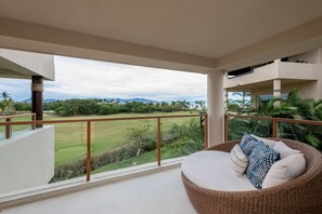 A balcony with a wicker sofa, a view of a golf course, and a clear sky. - Condo Silver in Punta Mita (Punta de Mita)