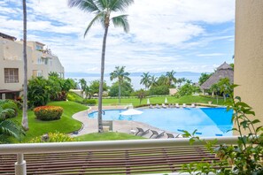Ett semesterparadis med en swimmingpool, palmer och utsikt över havet.