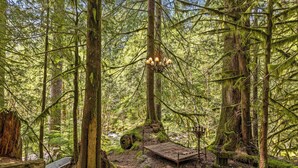 A forest with a wooden bench, a metal sculpture, and a hanging light fixture. - Waterfront lodge on 24 acres with patio & fireplace (Rhododendron)