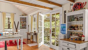 A room with a wooden ceiling, a dining table, a kitchen area with a water dispenser, and a view of a deck. - Waterfront lodge on 24 acres with patio & fireplace (Rhododendron)