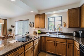 A kitchen with wooden cabinets, granite countertops, a sink, and a window with blinds. - 3BR Townhouse Near SHARC & Village - Dog Friendly (Sunriver)