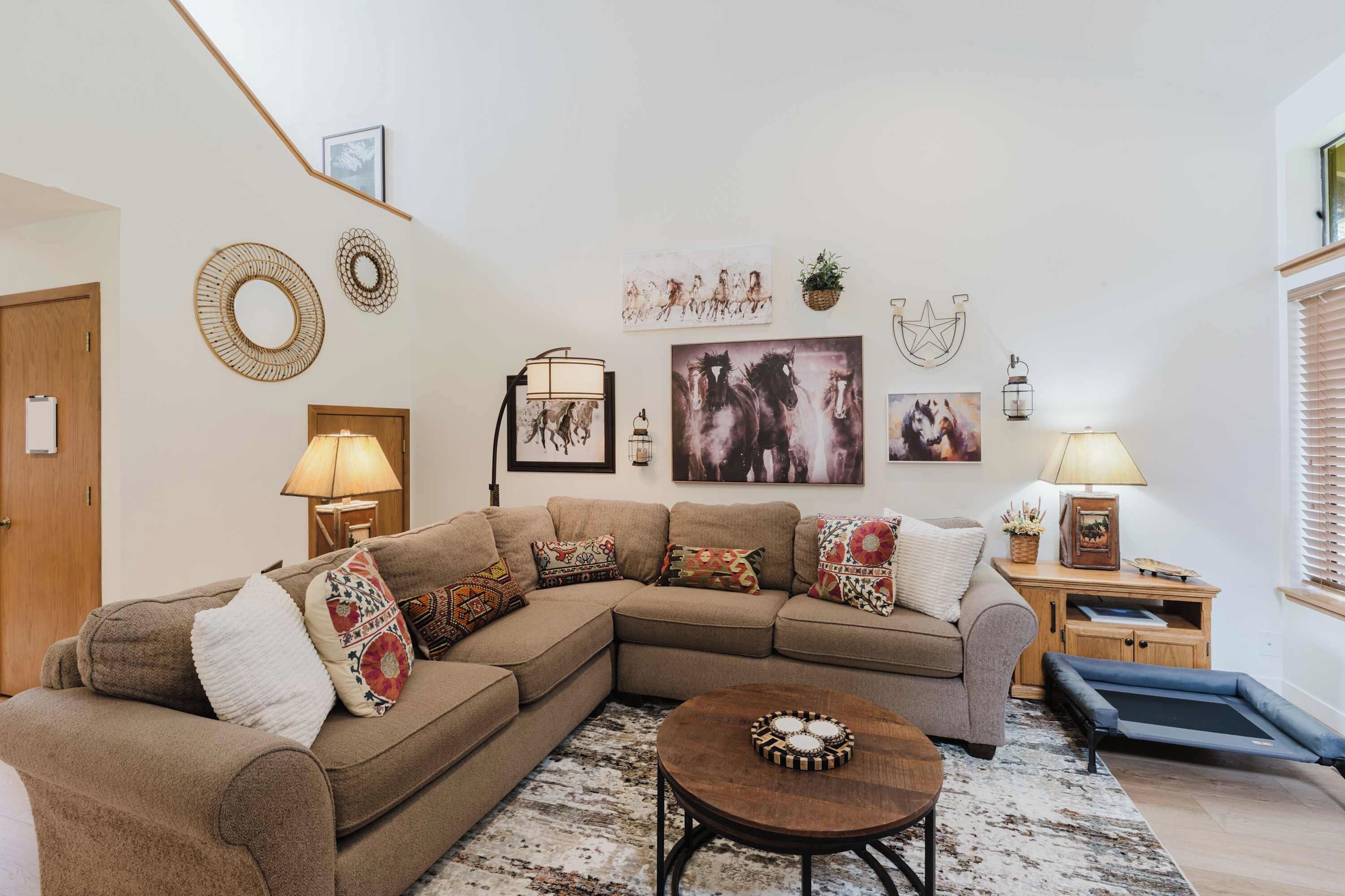 A living room with a sectional sofa, a round coffee table, and wall art.