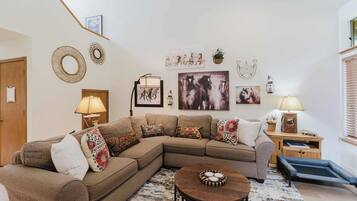 A living room with a sectional sofa, a round coffee table, and wall art.