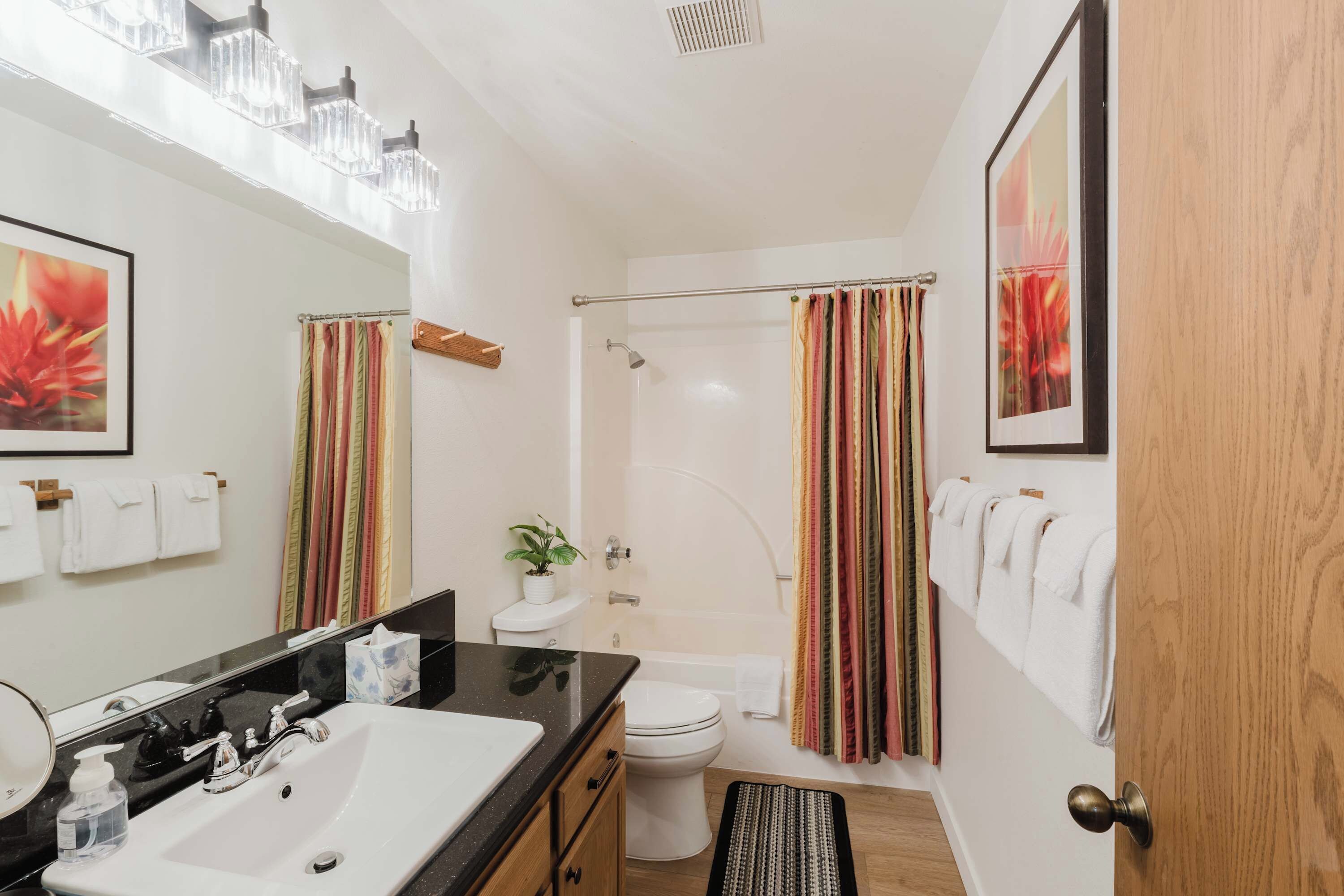 A bathroom with a sink, toilet, shower, and a mirror.