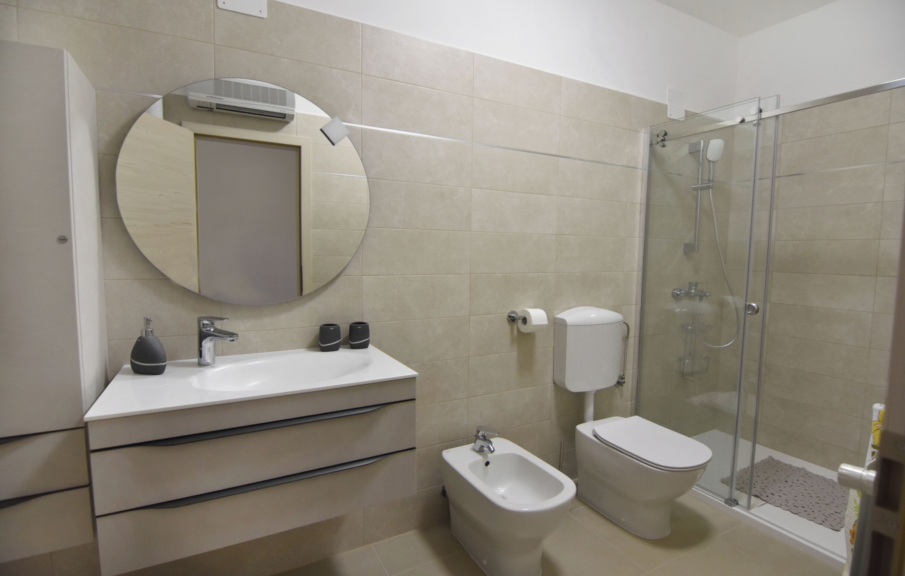 A bathroom with a sink, bidet, toilet, and a glass-enclosed shower.