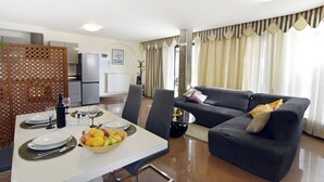 A modern living room with a sofa, dining table, and kitchen area. - Premium Stay With Terrace and BBQ (Umag)
