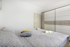 Ein Schlafzimmer mit Bett, Kissen, Nachttisch und Kleiderschrank.