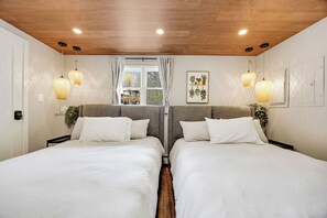 Ein Doppelzimmer mit Holzboden, zwei Nachttischlampen und einem Fenster mit Vorhängen.