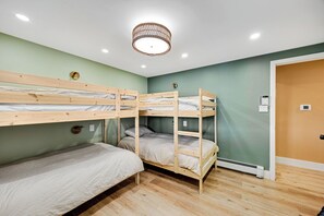 A bunk bed room with a ceiling light fixture and a door on the right.