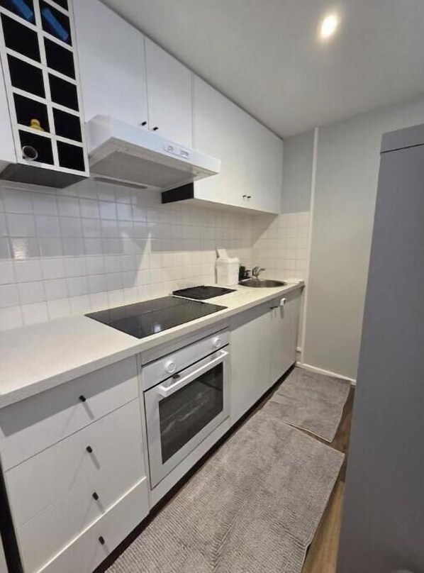 A modern kitchen with white cabinetry, a black stovetop, and a built-in oven.