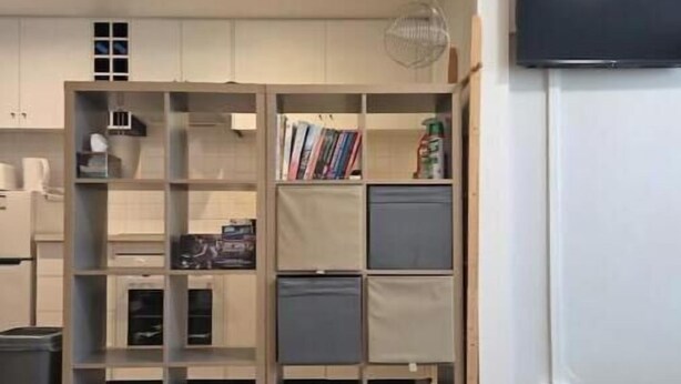 Een kamer met een ingebouwde boekenkast, een wandgemonteerde flatscreen televisie en een vloerbedekking.