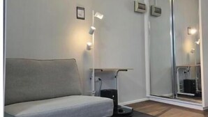 Een moderne kamer met een bank, een staande lamp, een schuifglazen deur en een klein tafeltje.