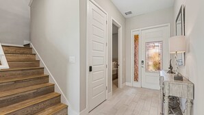 A staircase leading to a second floor, a door to a bathroom, and a hallway with a lamp and a decorative item. - Eagle Trace Birdie: Water Park, Golf View, Near Disney (Kissimmee)