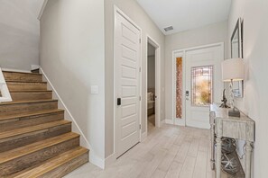 Eine Treppe führt zu einer zweiten Etage, eine Tür zu einem Badezimmer und ein Flur mit einer Lampe und einem dekorativen Gegenstand.