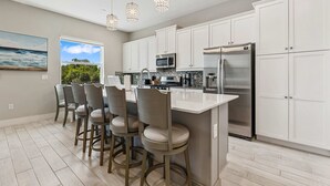 A modern kitchen with white cabinets, stainless steel appliances, and a central island with bar stools. - Eagle Trace Birdie: Water Park, Golf View, Near Disney (Kissimmee)