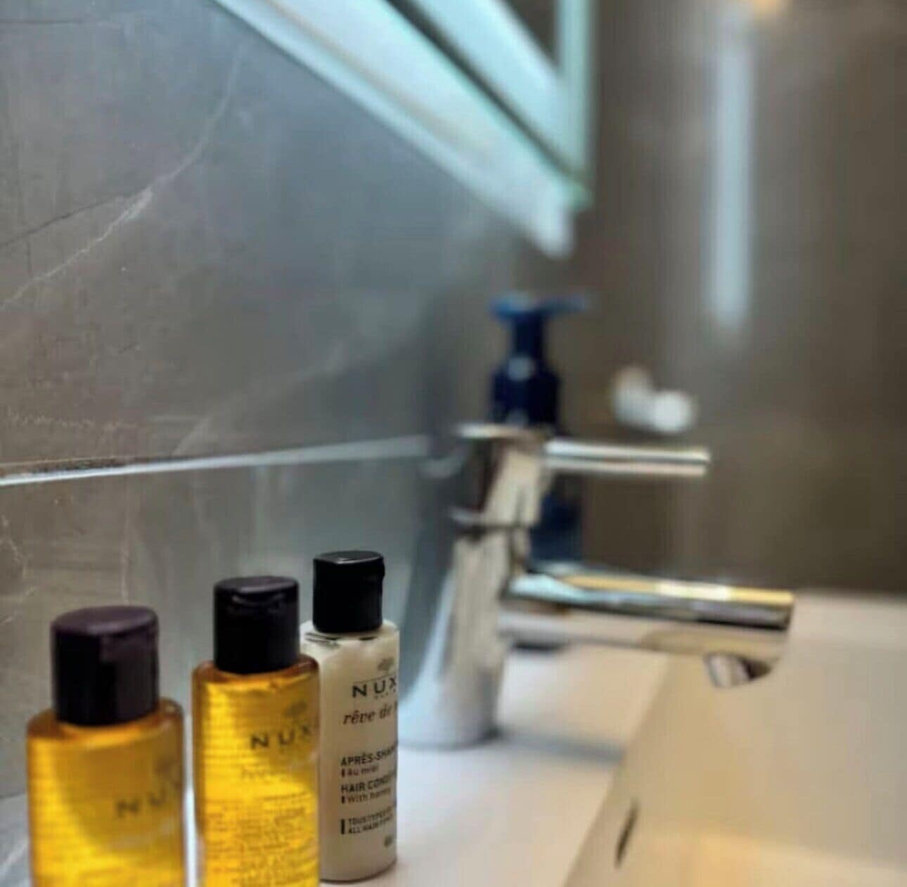 A bathroom with a sink, three toiletries, and a faucet.