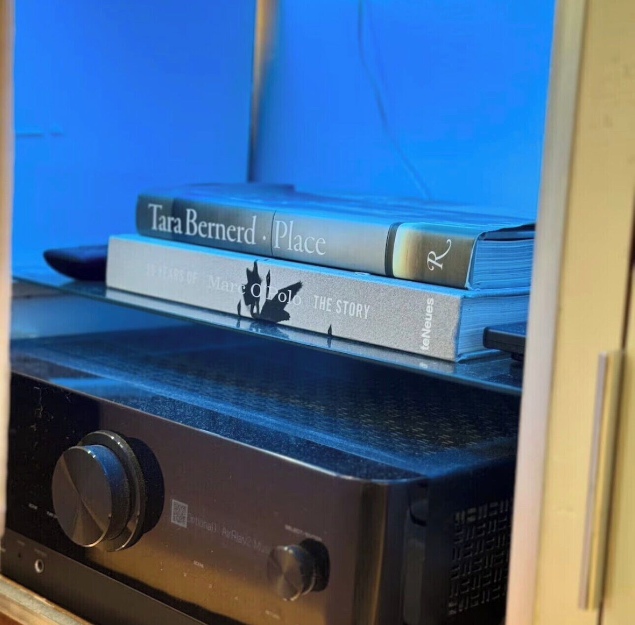 A bookshelf with books and a black audio device.