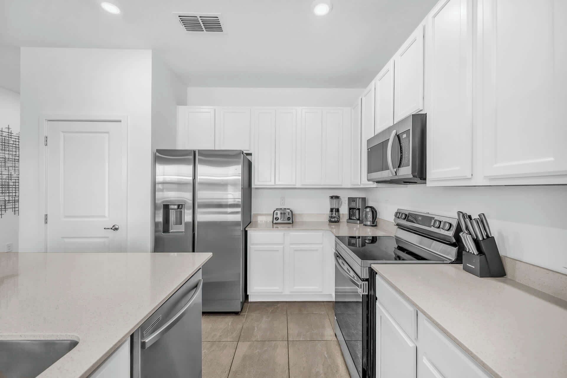 A modern kitchen with stainless steel appliances, white cabinetry, and a built-in oven.