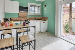 A kitchen with white cabinets, a window, and a view of the outside.