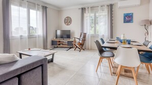 Un salon moderne comprenant un canapé, un téléviseur, une table à manger, des chaises et un meuble pour téléviseur.