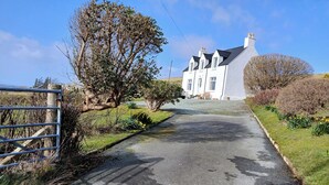 A rural road leading to a white house with a steep driveway.