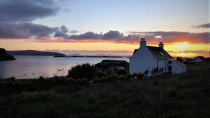 A coastal scene with a white building, a body of water, and distant hills.