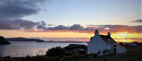 A coastal scene with a white building, a body of water, and distant hills.