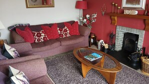 A living room with a sofa, a coffee table, a fireplace, and a mirror on the wall.