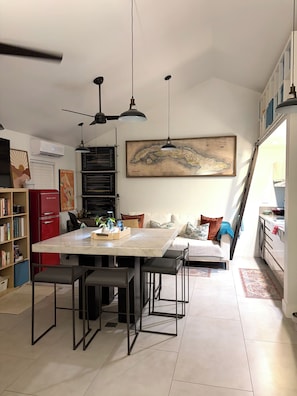 A modern kitchen with a dining area, a large map on the wall, and a ceiling fan. - Modern Studio Retreat in the Redland (Homestead)