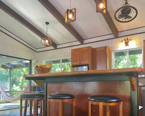 Una cocina con armarios de madera, un taburete de bar e iluminación colgante.