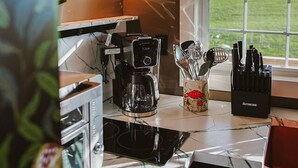 Una cocina con cafetera, utensilios y una ventana que ofrece vistas al exterior.