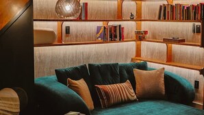 Una sala acogedora con un sofá modular, una mesa de centro y una estantería llena de libros.