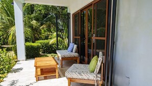 Eine Terrasse im Freien mit einer Holzbank, einem gepolsterten Stuhl und einem Tisch.