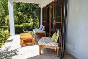 Une terrasse extérieure avec un banc en bois, un fauteuil rembourré et une table.