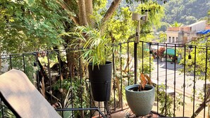 Ein Balkon mit Stuhl, Topfpflanzen und Blick auf eine Straße und Gebäude.