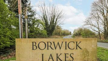 A sign for Borwick Lakes with a road in the background.