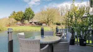 A deck with wicker furniture and a view of a lake. - Carp Lodge (Carnforth)