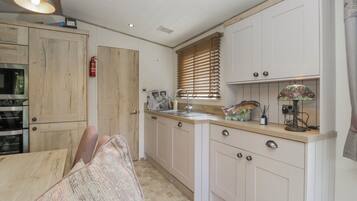 A kitchen with wooden cabinets, a sink, a stove, and a dining area with a chair.