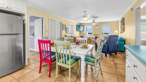 Une cuisine de taille réduite comprenant un réfrigérateur, une table à manger avec des chaises et un ventilateur de plafond.