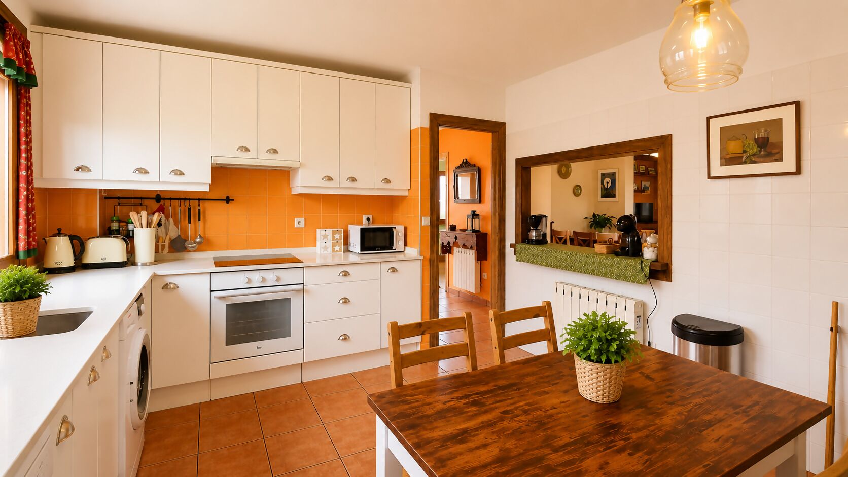 Uma cozinha compacta com armários brancos, micro-ondas, fogão e mesa de jantar com cadeiras.