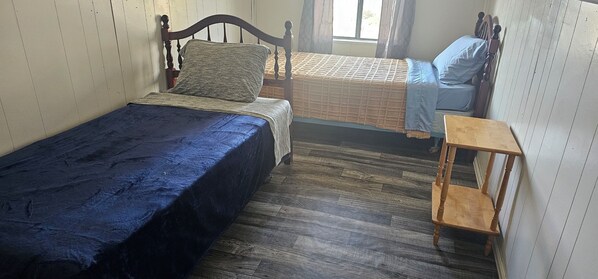 A room with two single beds, a wooden chair, and a small table.