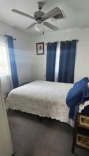 Ein Schlafzimmer mit einem Bett, einem Deckenventilator und Vorhängen.