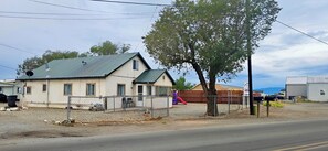 Una casa de una sola planta con techo verde, patio cercado y un parque infantil.