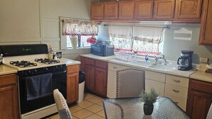 Une cuisine avec des meubles de rangement en bois, une cuisinière, un évier et un coin repas avec des chaises.